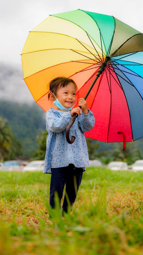 Girl in Blue Shirt Holding Rainbow-Colored Umbrella 