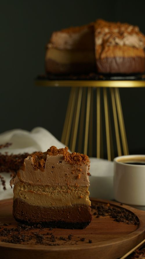 Free Gourmet layered coffee cake slice served on a wooden plate with a cup of coffee, perfect for dessert lovers. Stock Photo