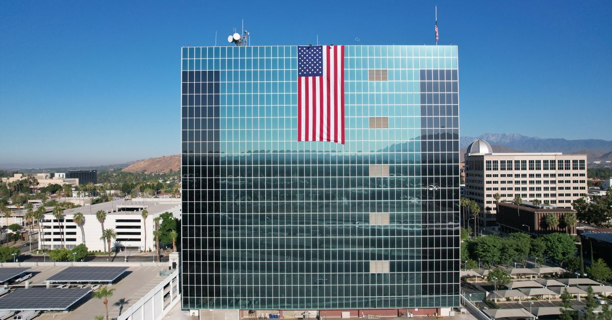 Stunning aerial shot of the Riverside County Administrative Center with American flag, showcasing urban landscape and architecture.