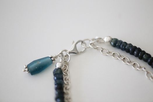 Detailed view of a silver necklace clasp and beaded chain with blue accents.