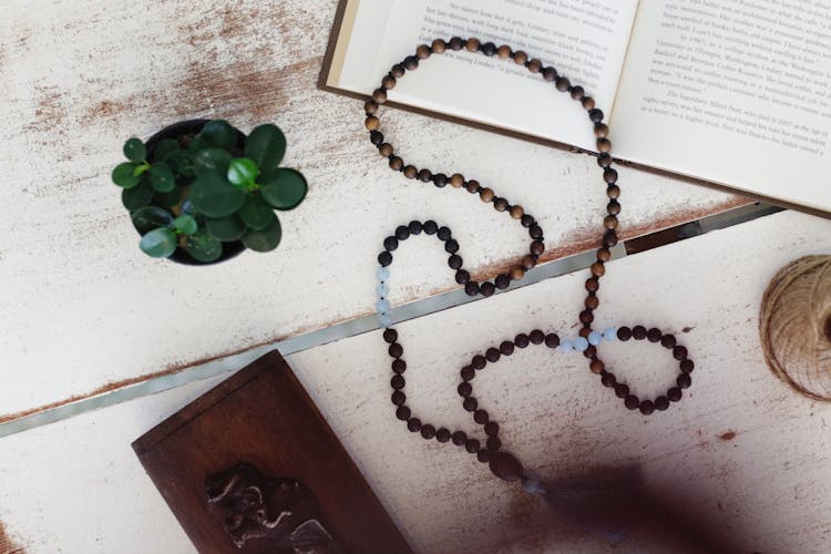 Rosary Lying On Open Book On Wooden Table