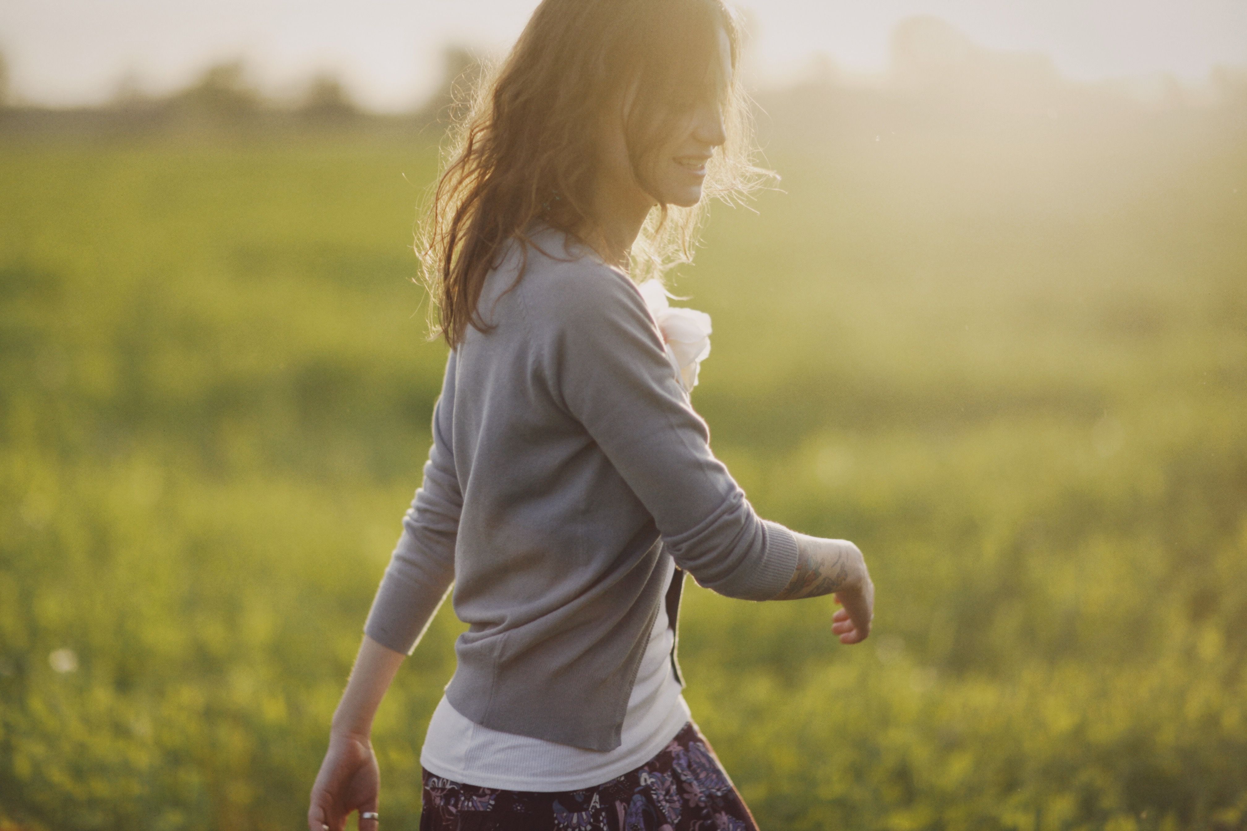 A cheerful woman walking in a sunlit field, embracing a carefree moment.