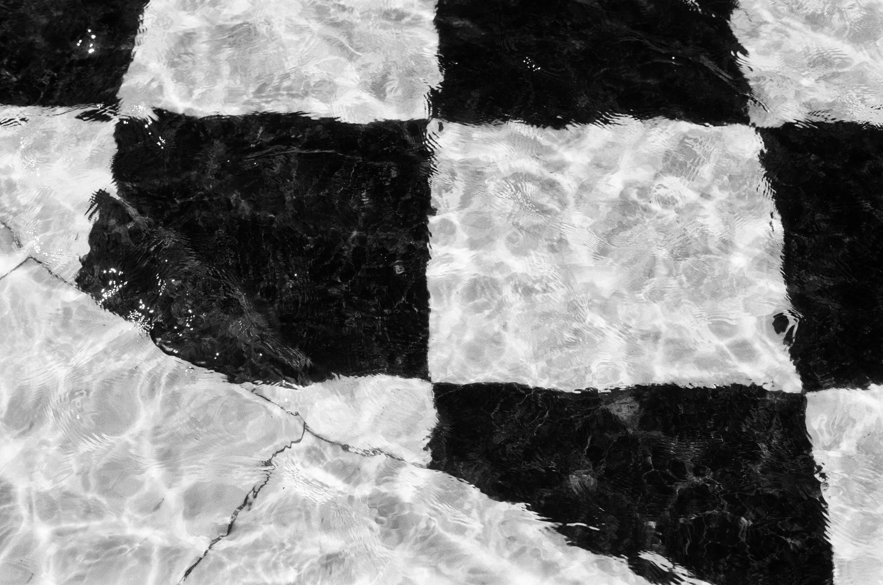 Artistic black and white checkered tiles submerged underwater creating a unique visual pattern.
