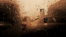 车窗上雨滴模糊了背景的车辆，营造出忧郁的氛围