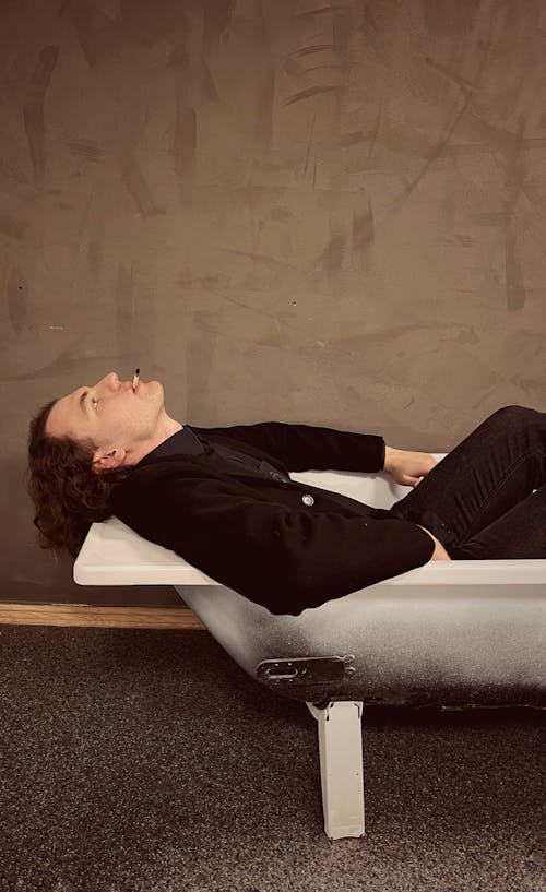 Man Lying on a Bathtub While Smoking Cigarette