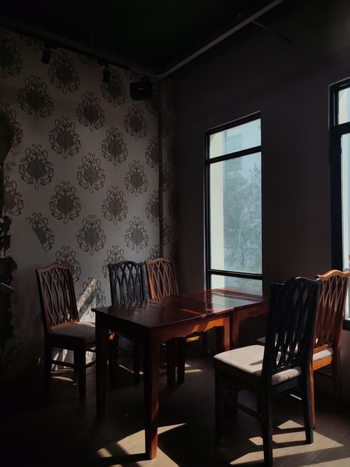 Free Elegant dining room with wooden furniture, natural light and floral wallpaper in Biên Hòa, Vietnam. Stock Photo