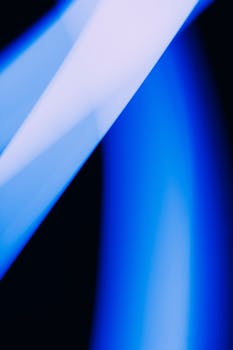 Abstract photo with dynamic blue and white light streaks on a dark background, capturing motion and contrast.