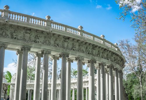 Free Elegant Roman-style colonnade with sculptures and columns viewed against a clear blue sky. Stock Photo