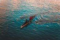 Three People on Brown Canoe Sailing on Calm Water