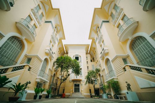 Free Low angle view of a stylish yellow building courtyard with ornate balconies and lush greenery. Stock Photo