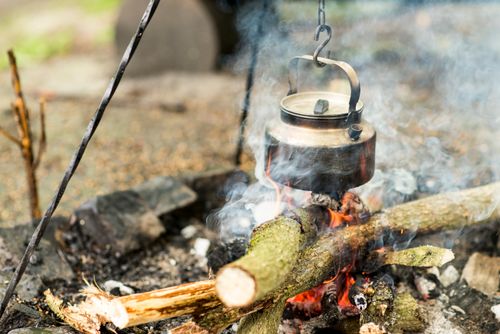 Free A traditional kettle hanging over a campfire, exuding a rustic outdoor cooking atmosphere. Stock Photo