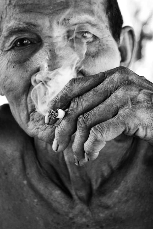 Grayscale Photo of an Elderly Man Smoking Cigarette