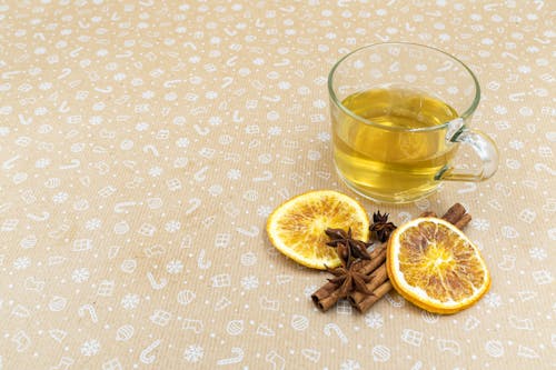A Cup of Hot Tea Beside Cinnamon Sticks and Lemon Slices