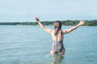 一名女子穿着泳衣，在热带海滩的水域中快乐地举起双臂，尽显自由与放松