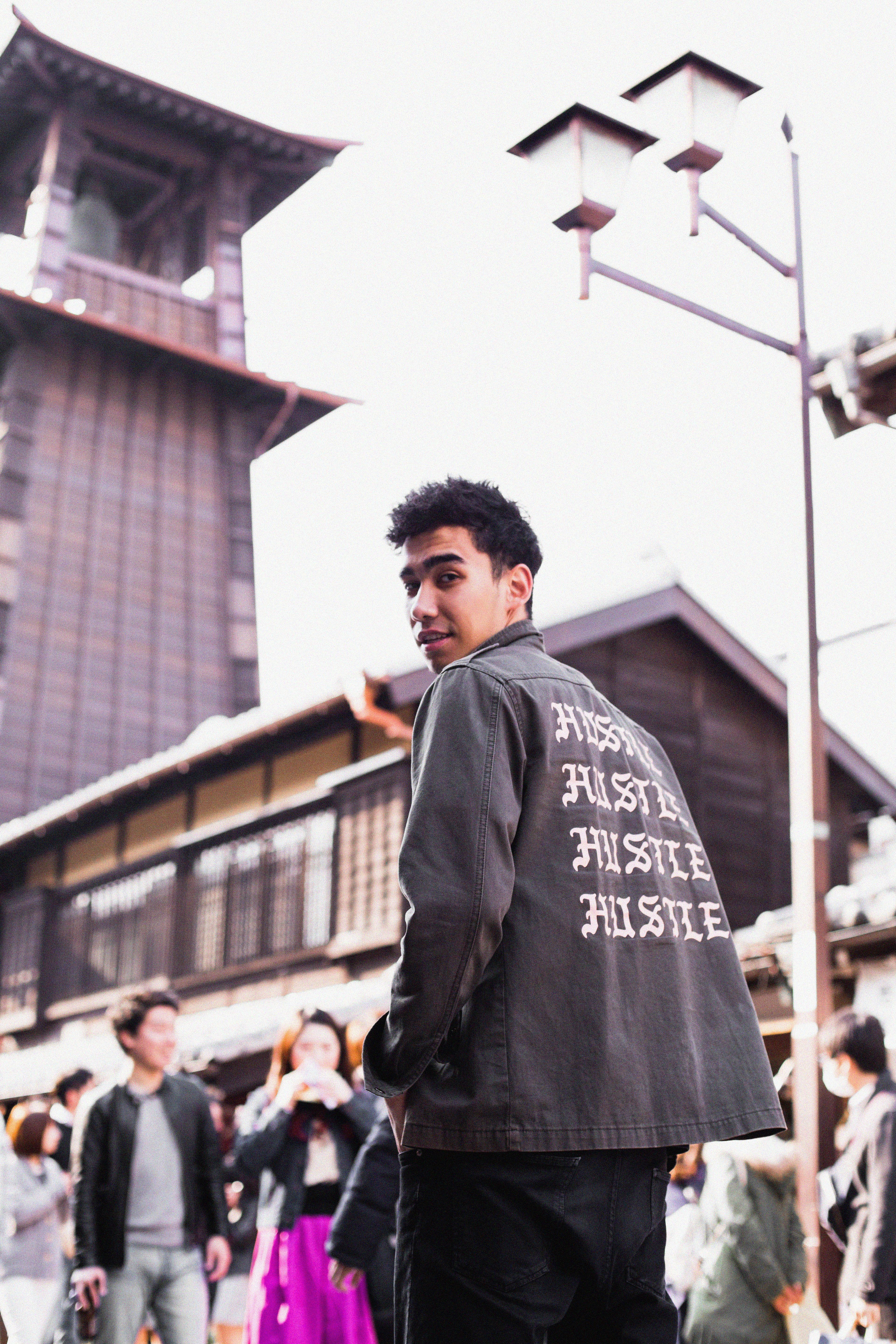 Young man in stylish jacket poses in Kawagoe's historic streets, showcasing urban fashion.