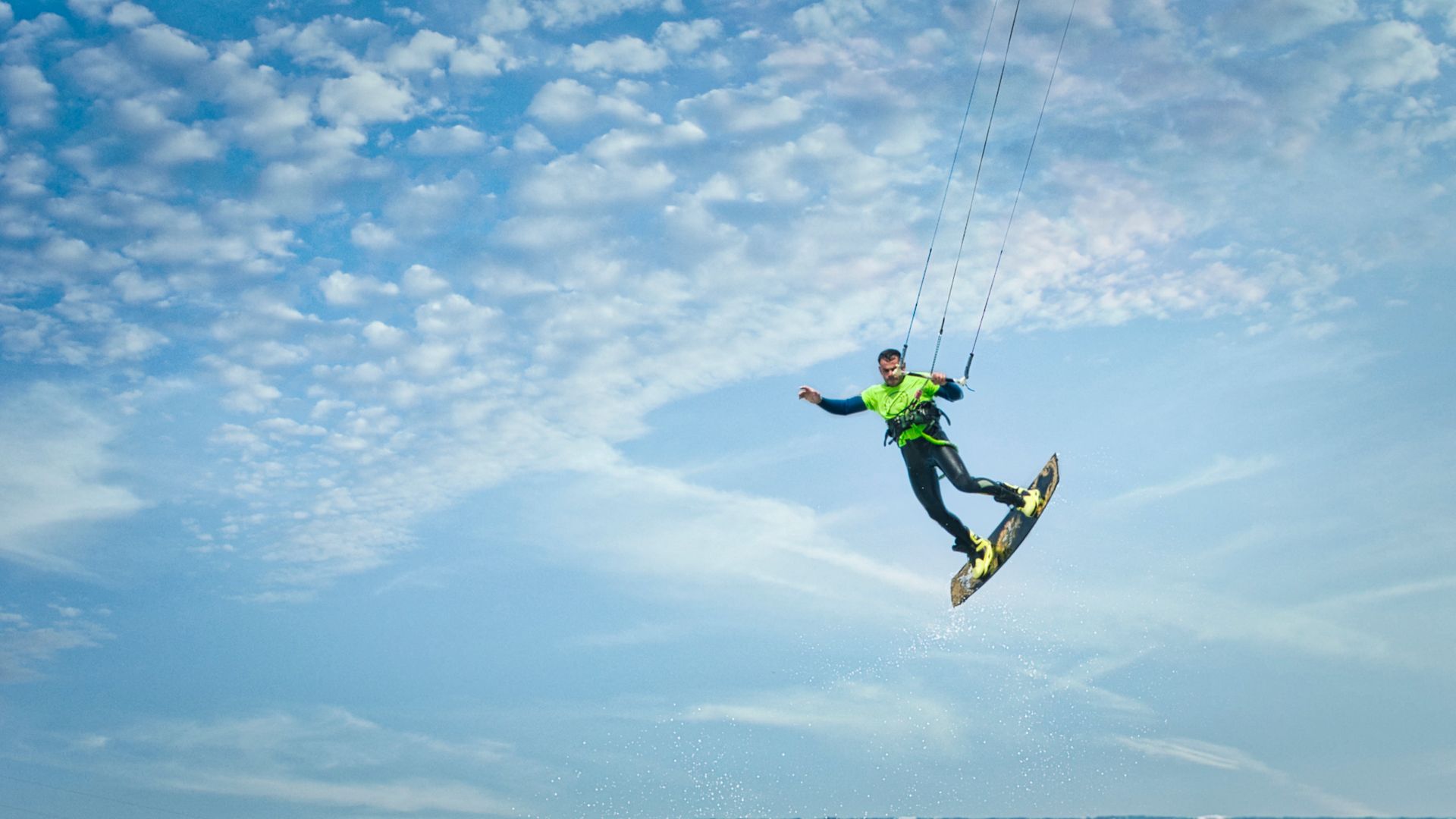 An exhilarating capture of kiteboarding action against a vivid blue sky, embodying freedom and adventure.