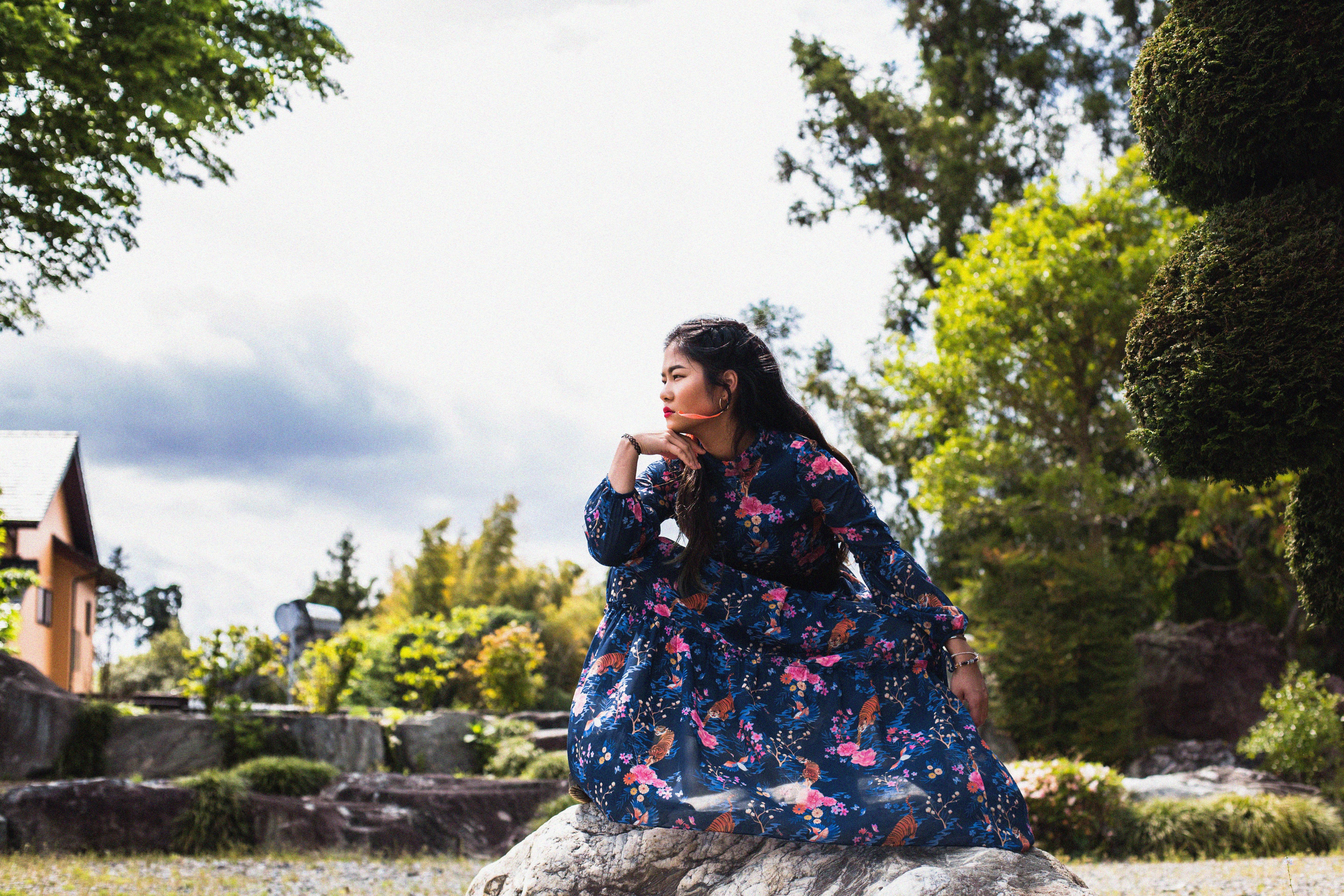 A Woman in Blue Dress Sitting on Big Rock while Looking Afar · Free ...