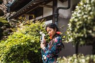 Woman in Blue Red and Green Floral Long Sleeve Dress Holding Gray and Black Microphone