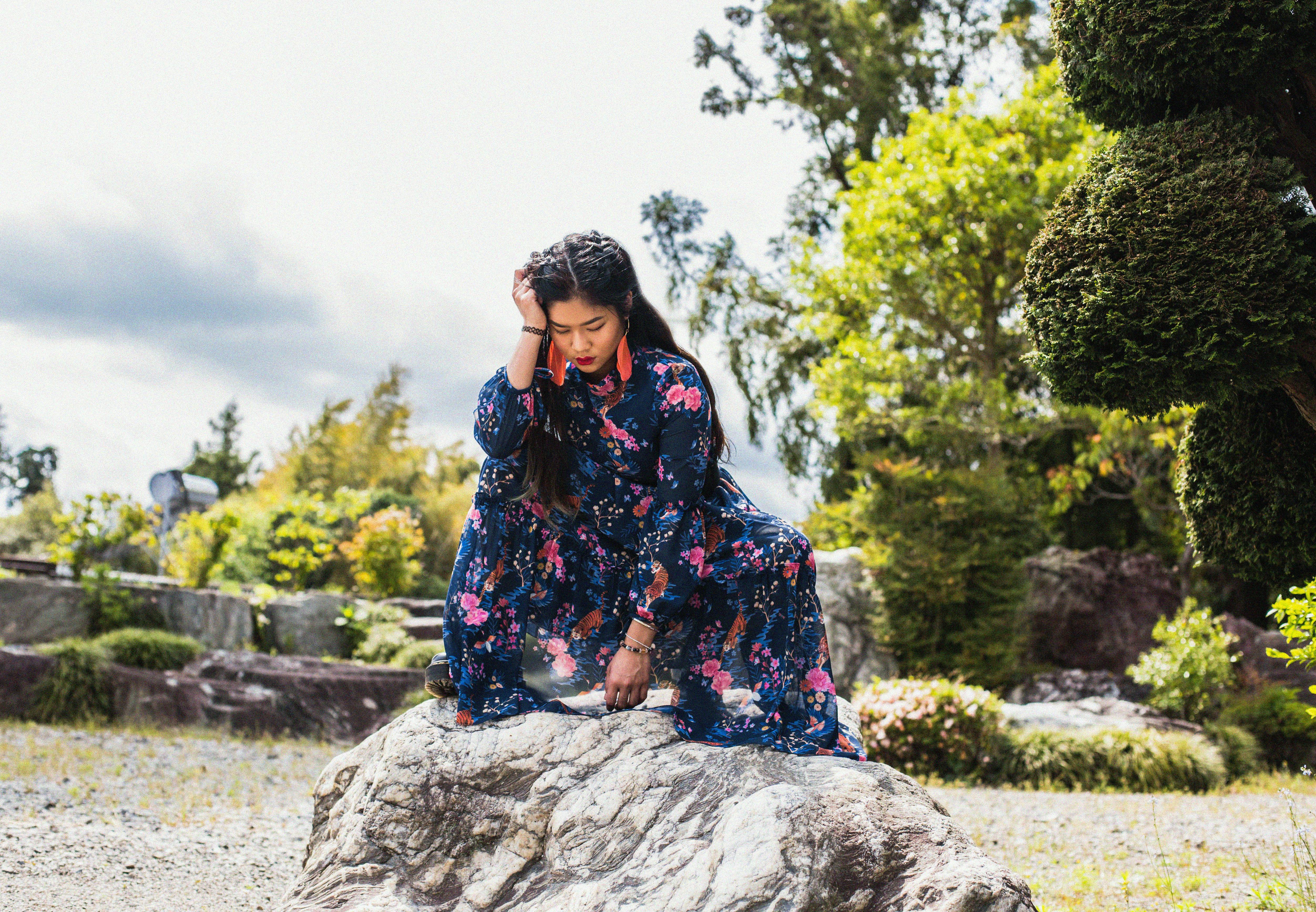 A Woman in Floral Dress Sitting on Big Rock while Looking Down · Free Stock  Photo