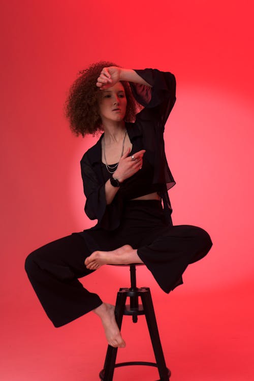 Woman in Black Blazer Sitting on a Chair while Posing at the Camera