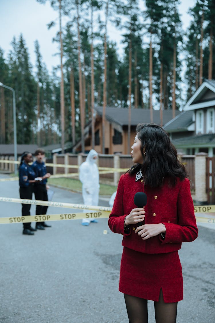 A Newscaster Reporting While Standing Near The Crime Scene