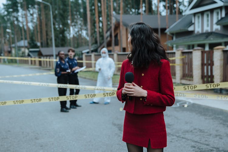 A Reporter Looking At The Crime Scene While Standing Outside The Barricade Tape