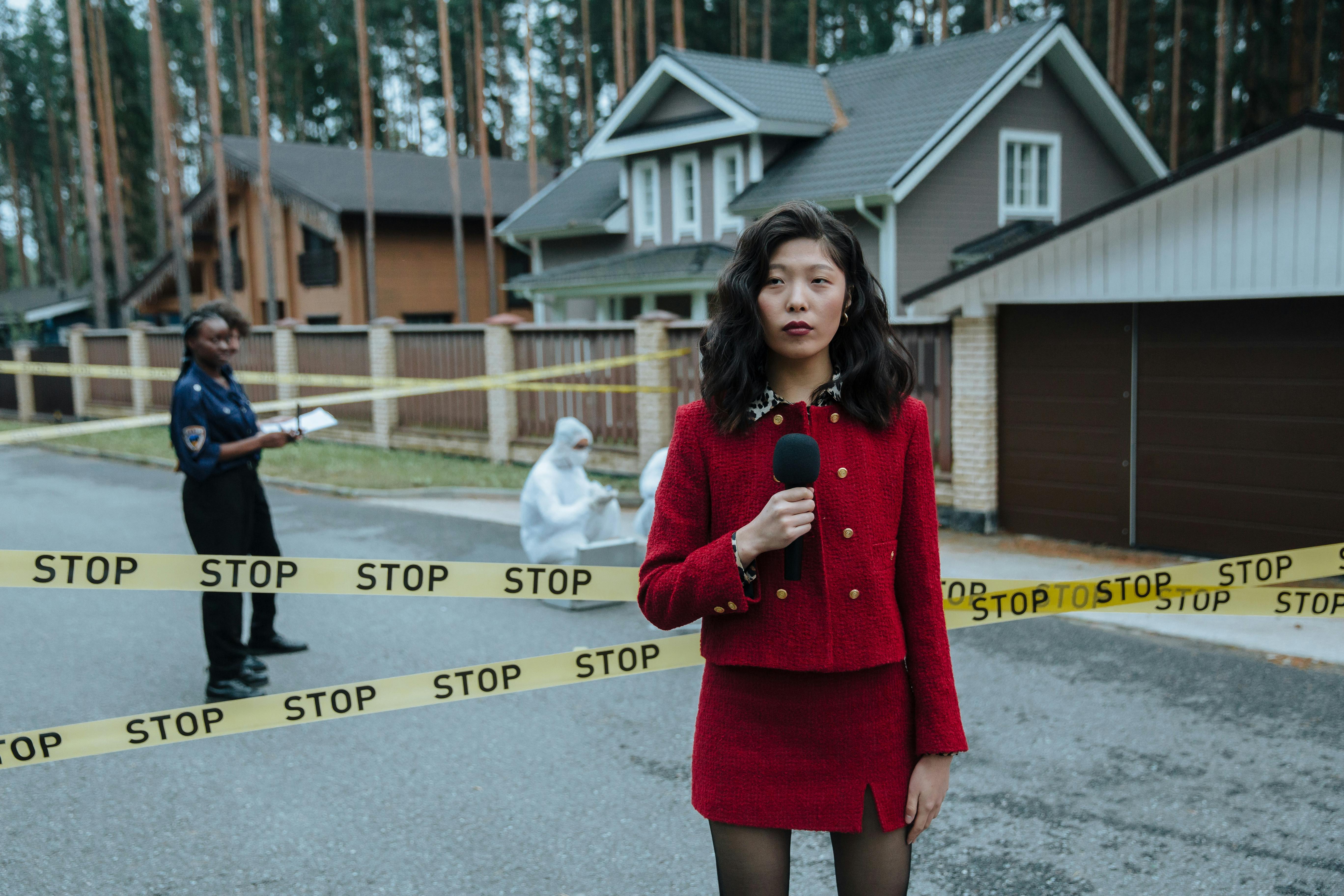 a woman wearing red outfit reporting in a crime scene