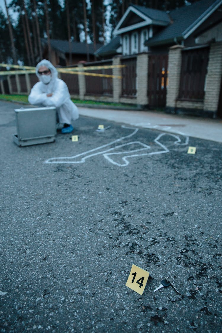 Person Sitting Beside A Chalk Outline At A Crime Scene