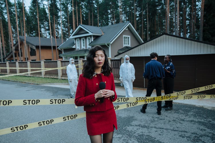 A Woman Wearing Red Outfit Reporting In A Crime Scene