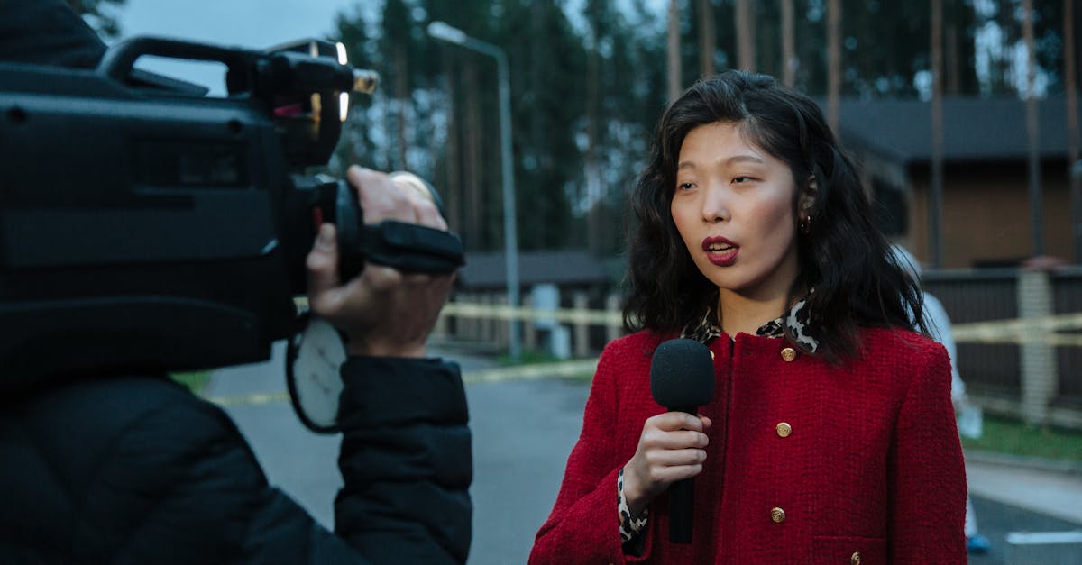 Asian female journalist reporting live from a suburban crime scene with camera and microphone.