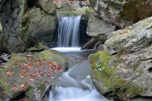 Serene waterfall flowing over mossy rocks in Horní Město, Czech Republic.
