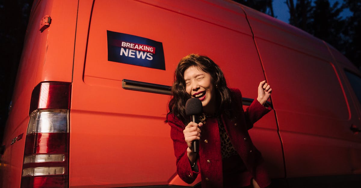 Asian woman reporter energetically broadcasting with a microphone in front of a news van at night.