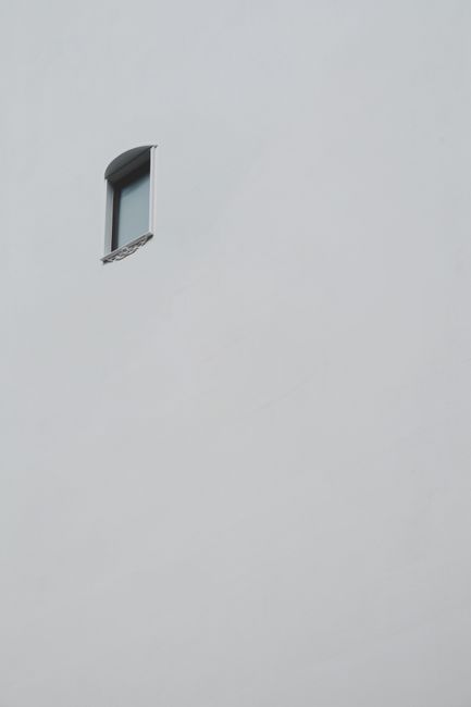 Simple minimalist architecture featuring a single window on a plain white wall.