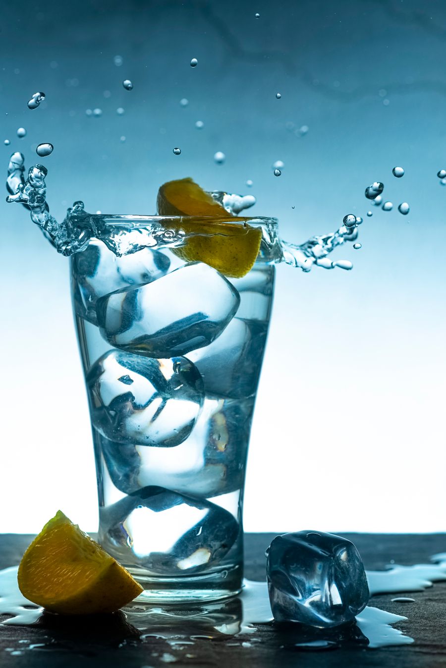 Close-up of lemon slices and ice cubes splashing in water in a dramatic freeze