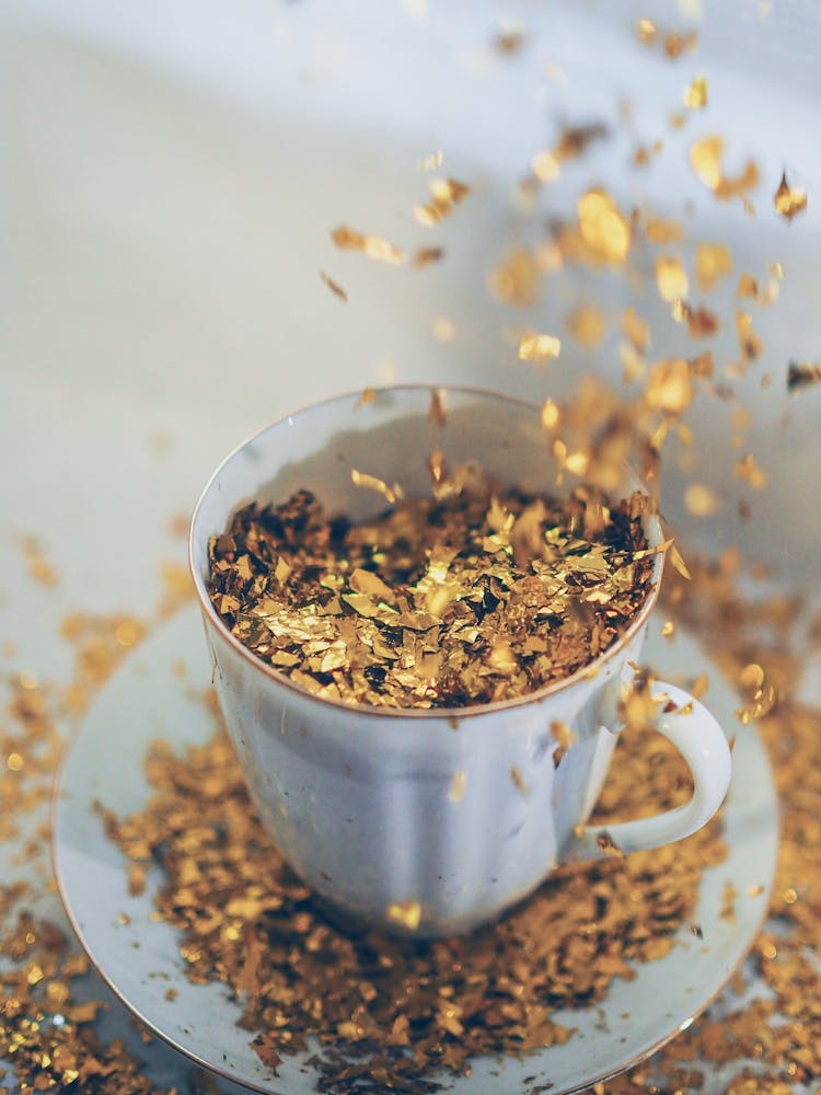 Gold Flakes Falling Into Porcelain Tea Cup