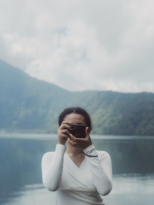 Woman in White Long Sleeve Shirt Taking Photo