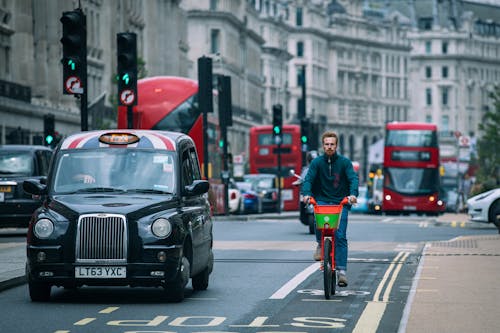 Free Man in Green Jacket Riding Bicycle on Road Stock Photo
