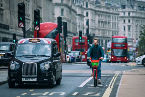 Free A cyclist riding amidst traffic in London's bustling streets. Stock Photo
