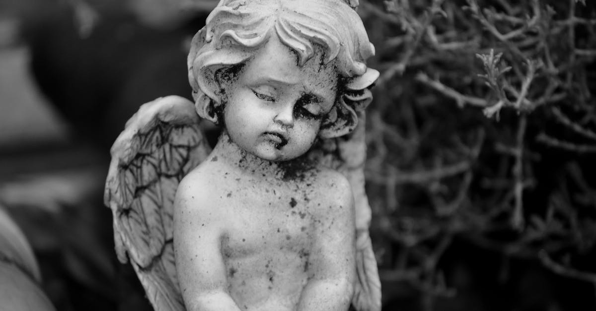 A tranquil angelic figurine photographed in grayscale, exuding a peaceful ambiance outdoors.