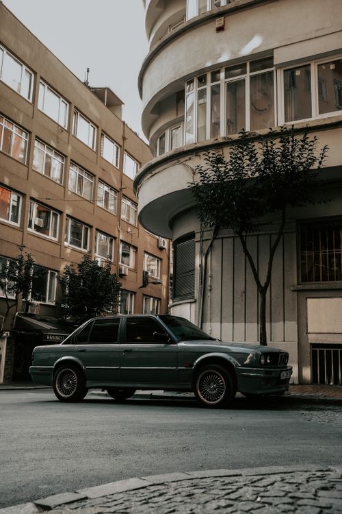 Free A vintage car parked on an urban street surrounded by modern architecture. Stock Photo