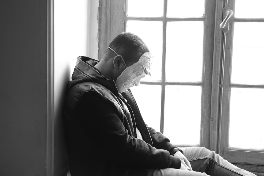 Free Man Wearing Mask Sitting Near Window Panel Stock Photo