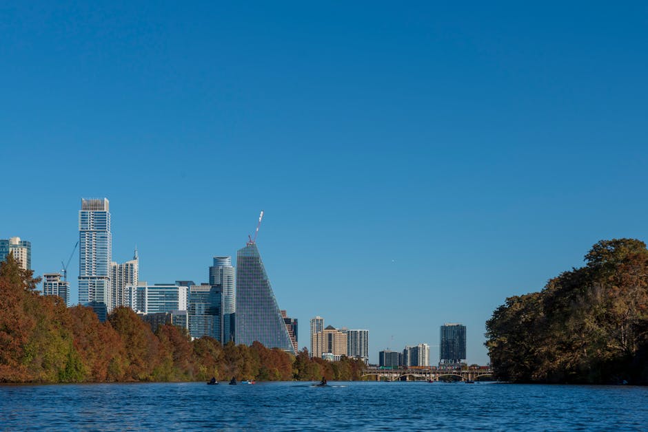 Beautiful view of the Austin skyline with skyscrapers reflecting on the river under a clear blue sky.