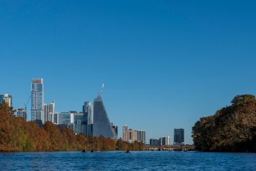 Free Beautiful view of the Austin skyline with skyscrapers reflecting on the river under a clear blue sky. Stock Photo
