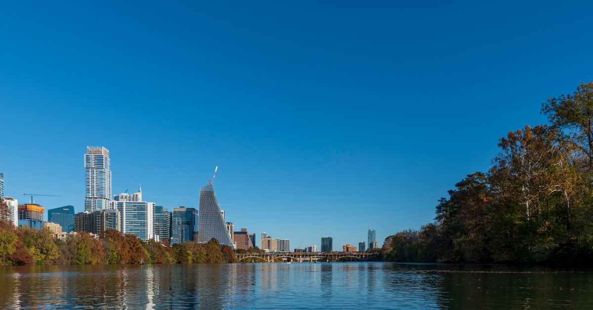 Beautiful view of Austin skyline against a clear blue sky over the Colorado River.