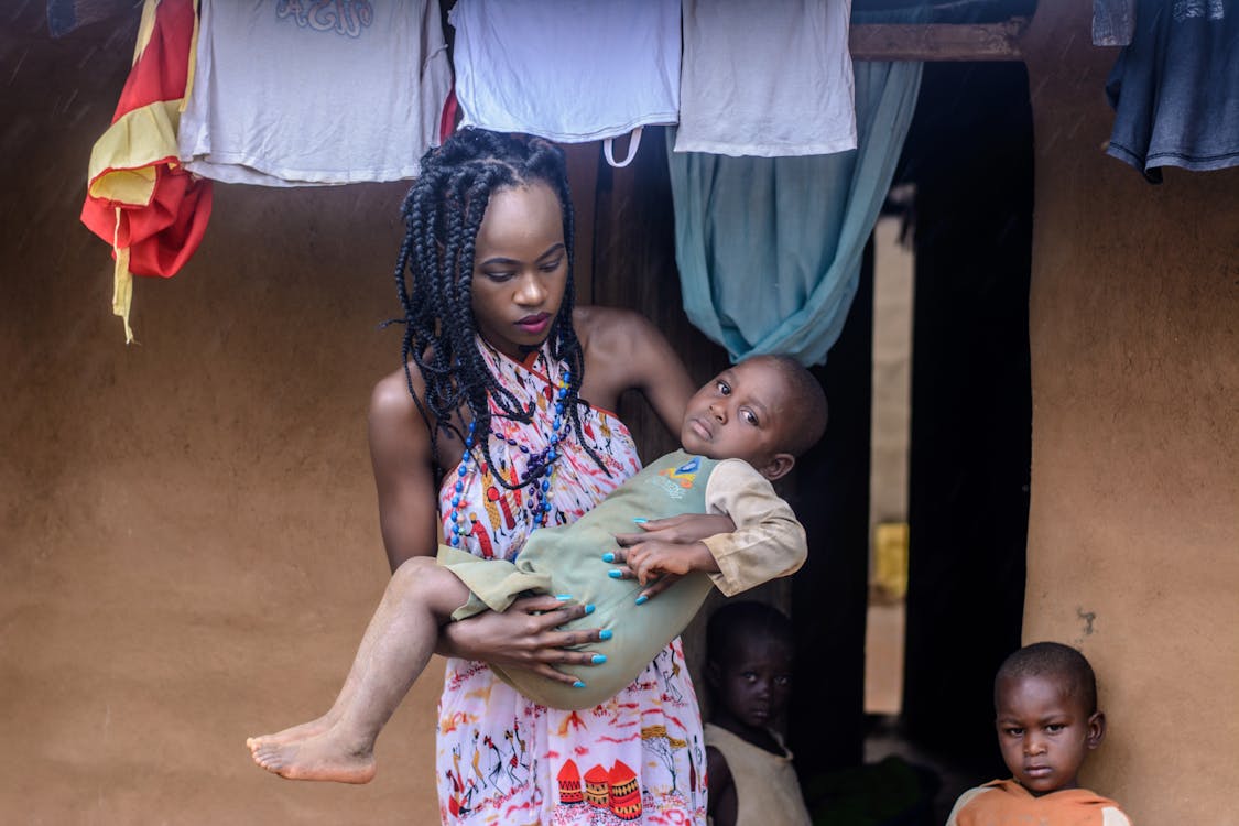 Woman in Multicolored Halter Dress Carrying Child