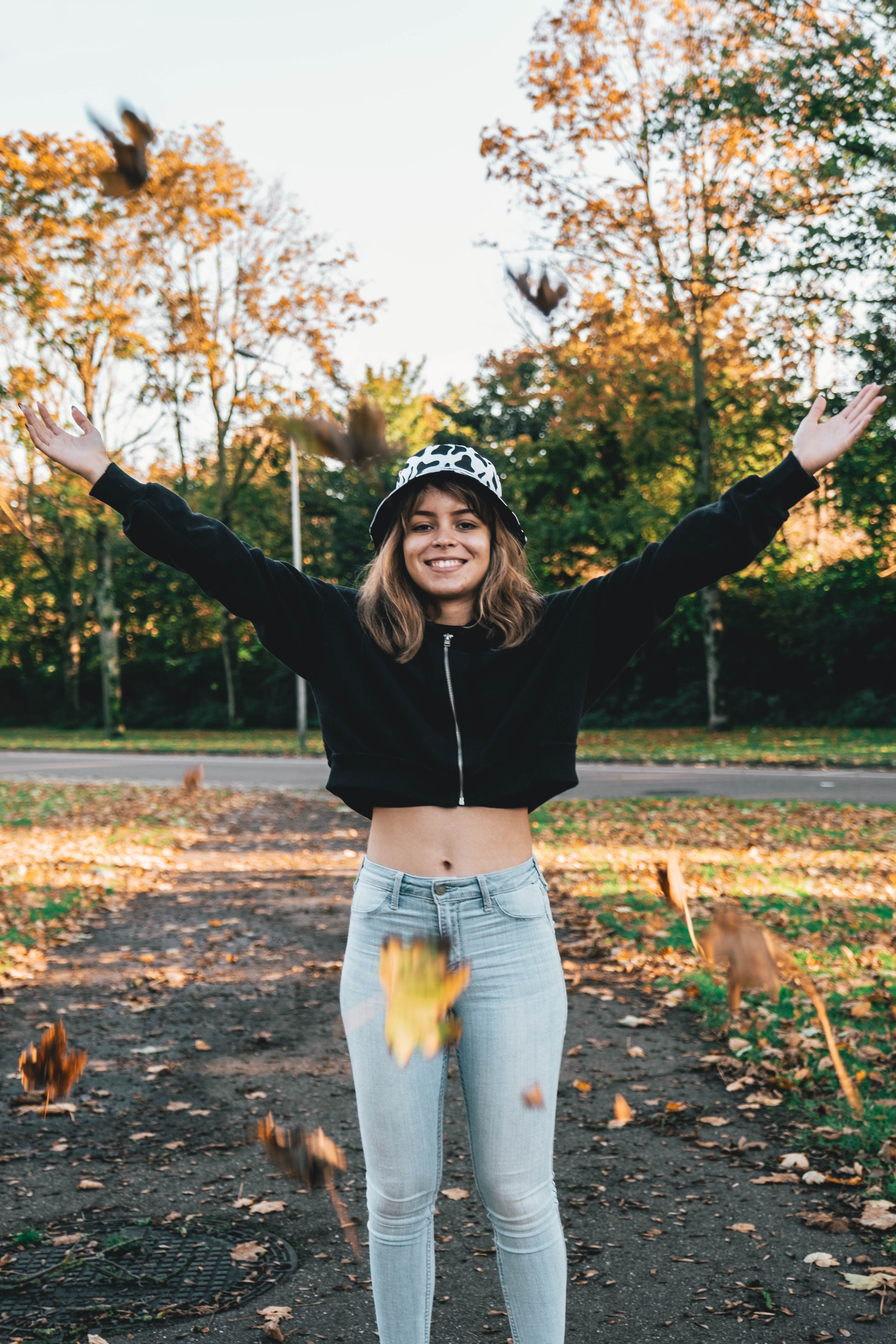 Young woman in denim enjoying fall foliage outdoors, radiating happiness.