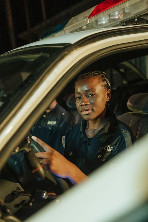 Free A female police officer sitting in a patrol car at night, looking attentively. Stock Photo