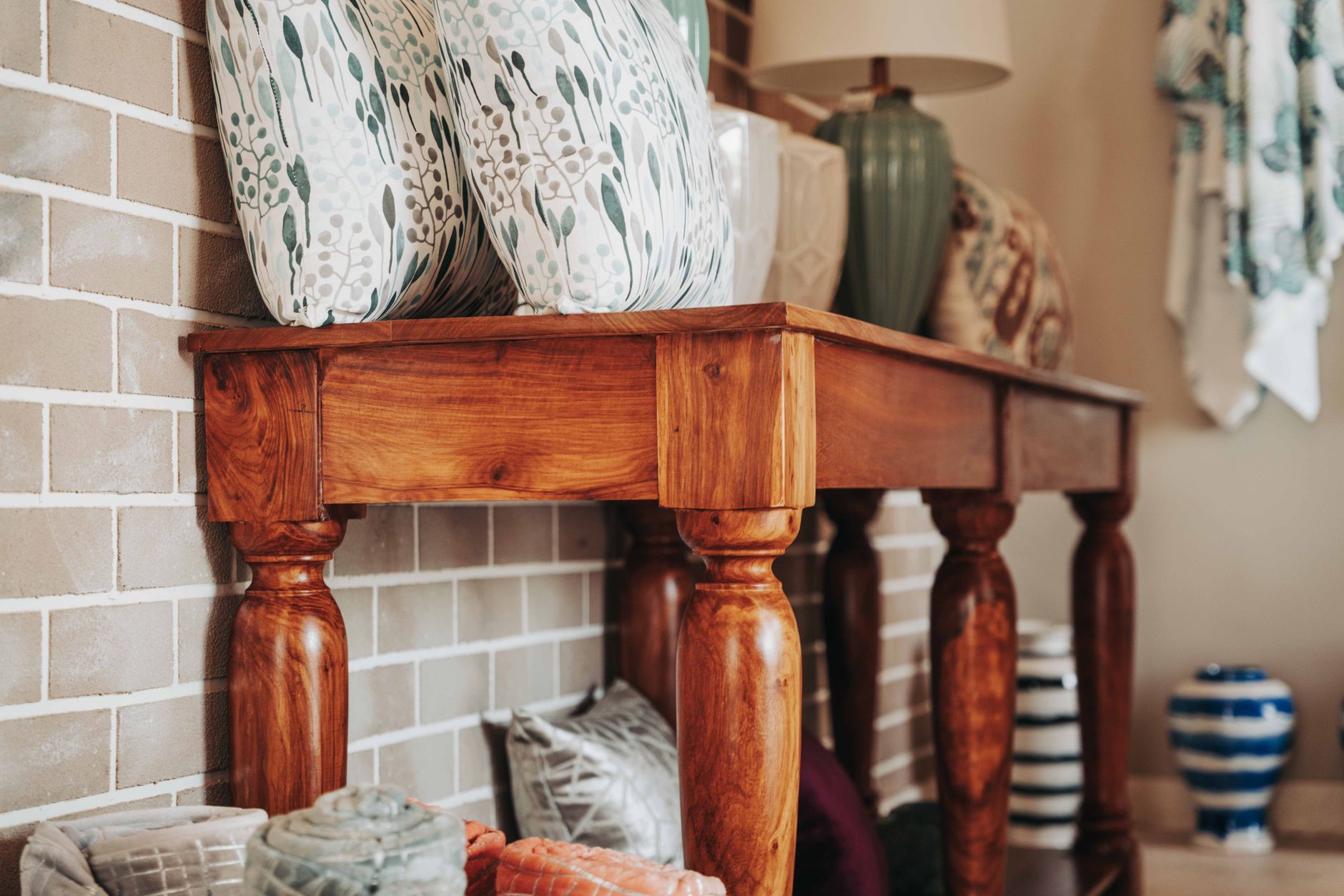 A stylish home interior featuring a vintage wooden console table with decorative pillows and lamps.