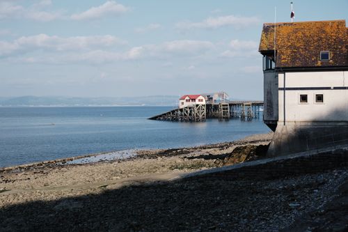 Free Tranquil coastal scene with pier and historic building under blue sky. Stock Photo