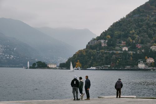 Free A group of people enjoying the view of Lake Como, surrounded by mountains and sailboats, in a peaceful setting. Stock Photo